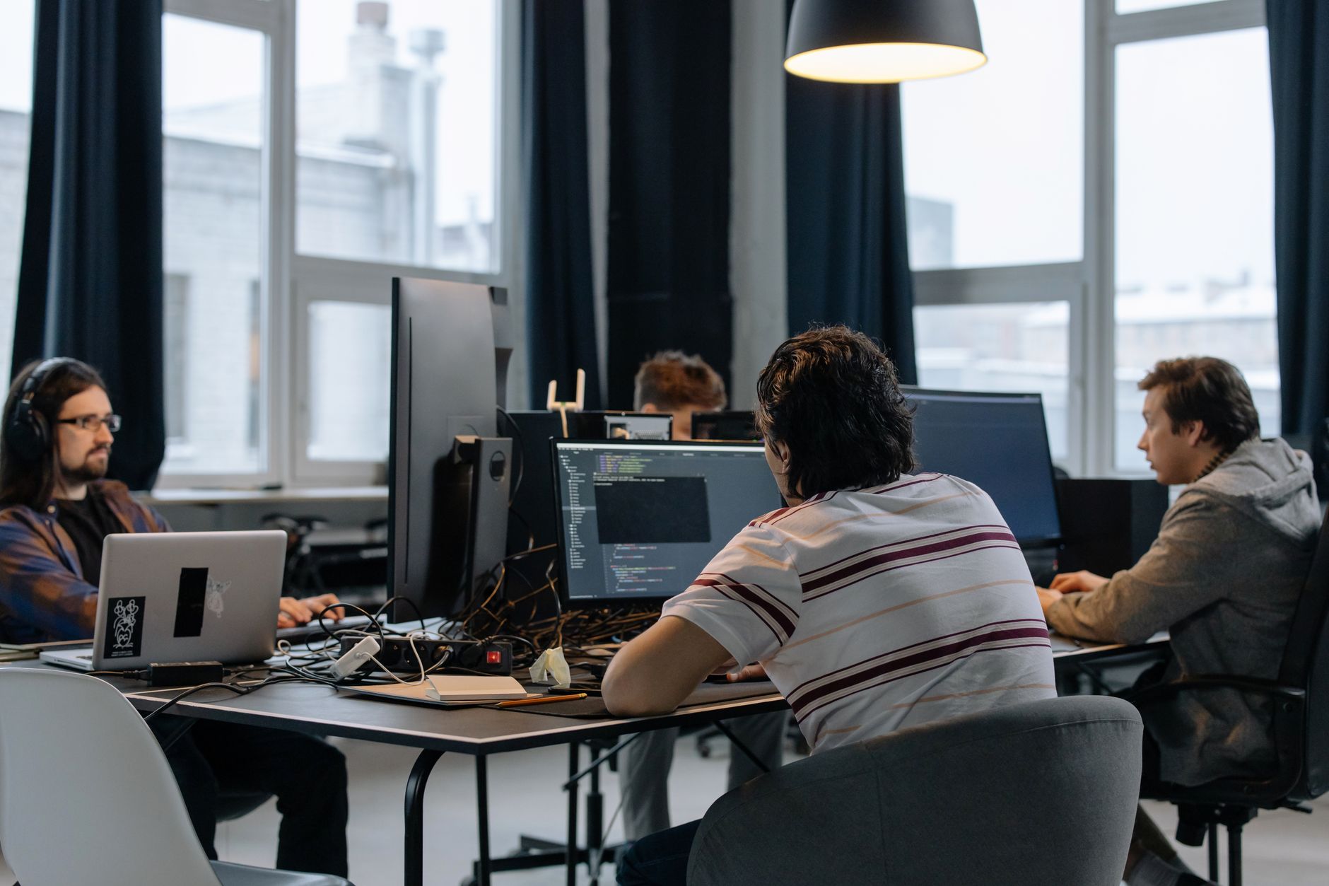 Tim programera radi za stolovima sa računarima u svetlom radnom prostoru